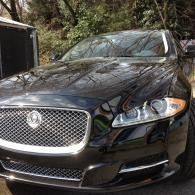 Black Jaguar sedan parked outdoors with a chrome grille and headlight visible