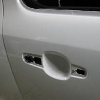 Close-up of a white car door handle with two damaged keyless entry buttons