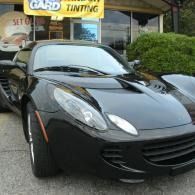 Black sports car parked outside a tinting shop