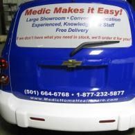 Blue Medic Makes it Easy van with large white advertising banner on the back, phone numbers visible