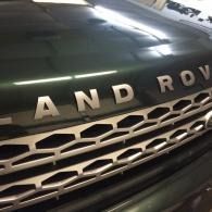 Close-up of a black Land Rover front grille and hood badge