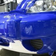 Blue sports car front bumper with chrome grille and headlight close-up