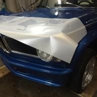 Blue car front covered with a white protective sheet in a garage