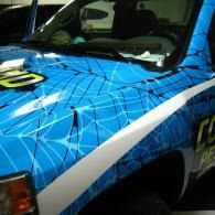 Blue graphic-covered car hood and fender with white diagonal stripe