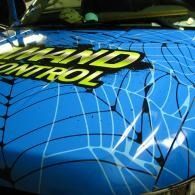 Blue car hood with spiderweb crack lines and yellow  text