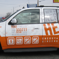 Orange-and-white Helix Energy & Ginseng taxi with phone number and ad decals on the side