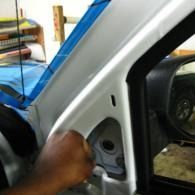 Hand opening a car door panel near the side mirror and white door frame