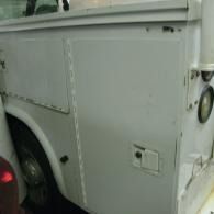 Side view of a white utility truck with a rear wheel and panel doors