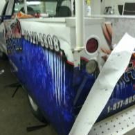 Custom blue-and-white truck wrap with graphics, parked indoors near a white pillar