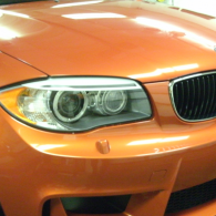 Close-up of an orange BMW car front headlight and grille