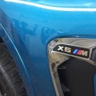 Blue BMW X6 M front fender badge and wheel arch close-up