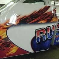 Flame-themed race car door with large blue and red “RUS” lettering