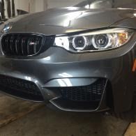 Front view of a gray BMW parked in a garage, showing the grille and headlights.