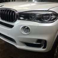 Front view of a white BMW SUV with a chrome grille and headlights.