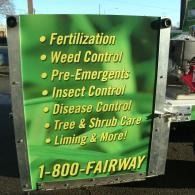 Green sign listing lawn care services: fertilization, weed control, insect and disease control, tree care, liming.