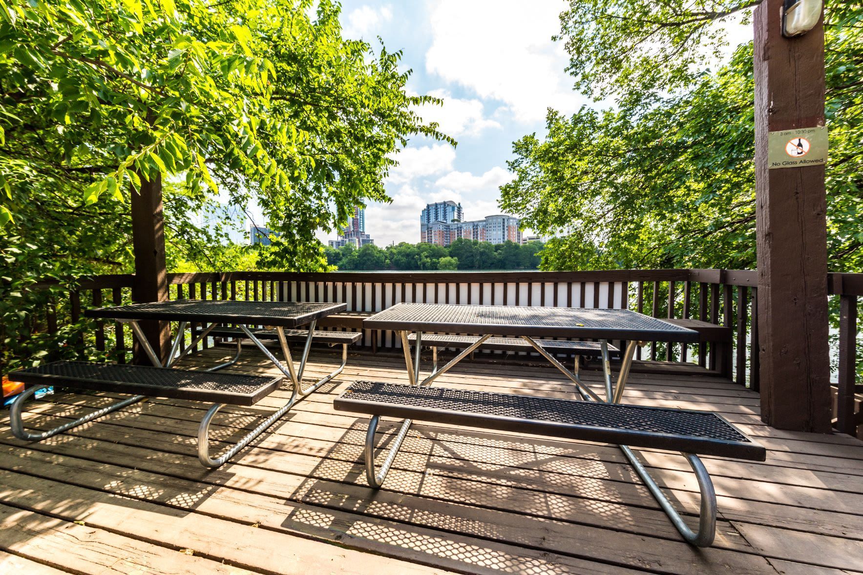 A picnic table and benches on a wooden deck overlooking a lake at SoCo on the Lake in Austin, TX.