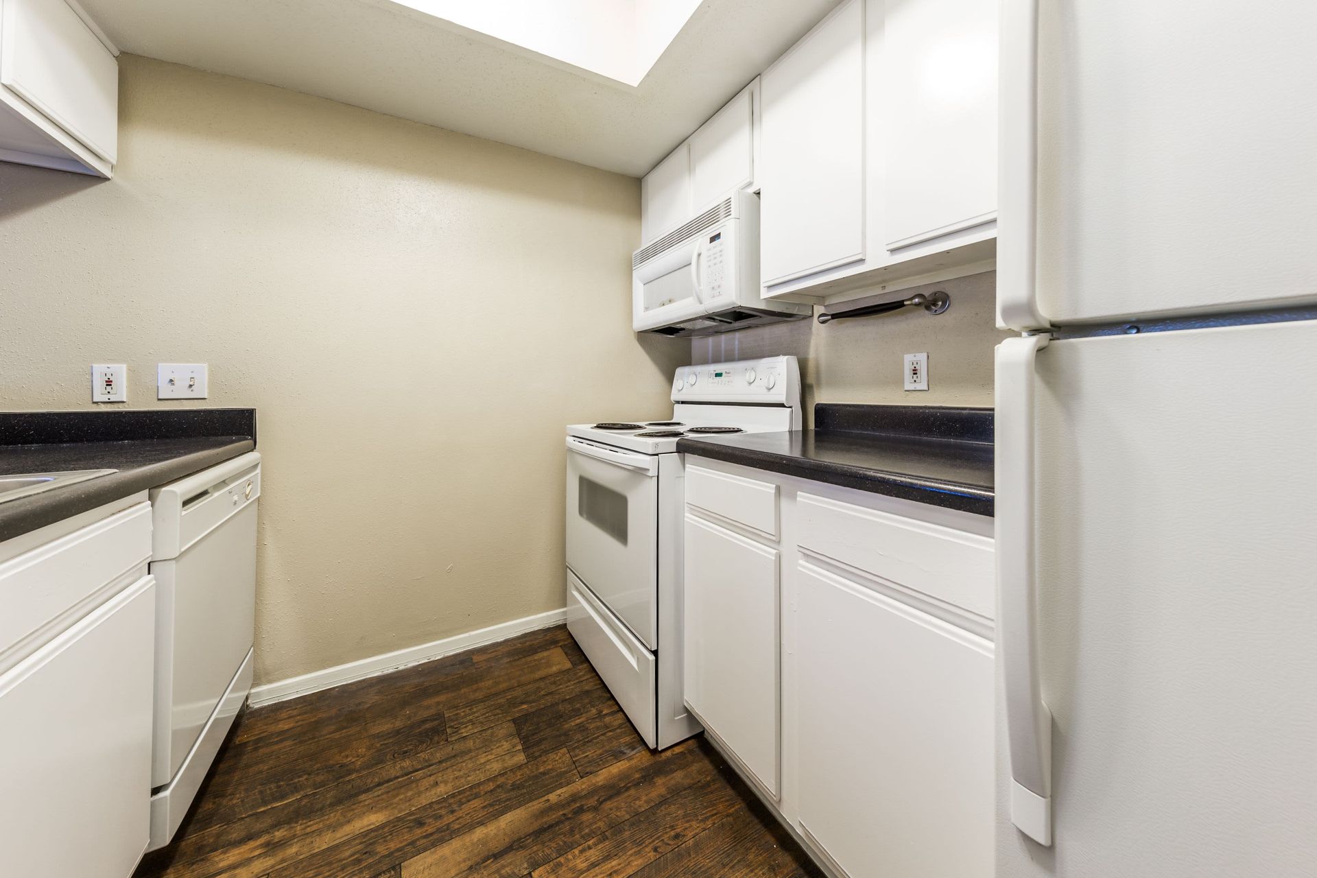 A kitchen with white cabinets, a stove, a refrigerator, and a dishwasher at SoCo on the Lake in Austin, TX.
