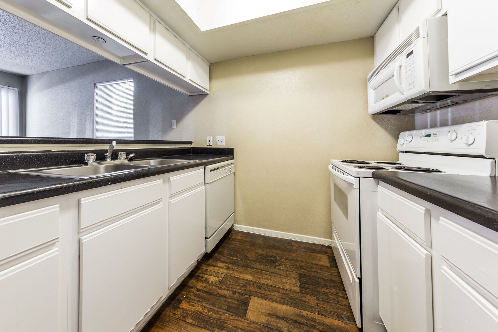 A kitchen with white cabinets, a stove, a sink, and a microwave at SoCo on the Lake in Austin, TX.