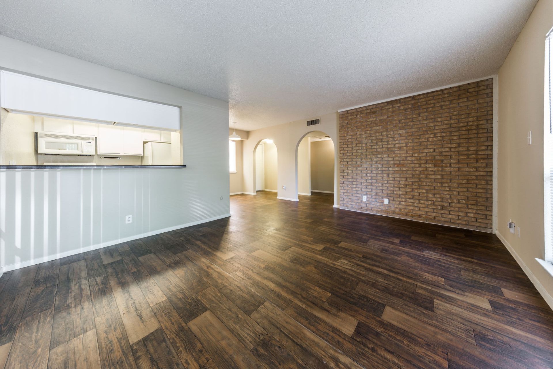 An empty living room with hardwood floors and a brick wall at SoCo on the Lake in Austin, TX.