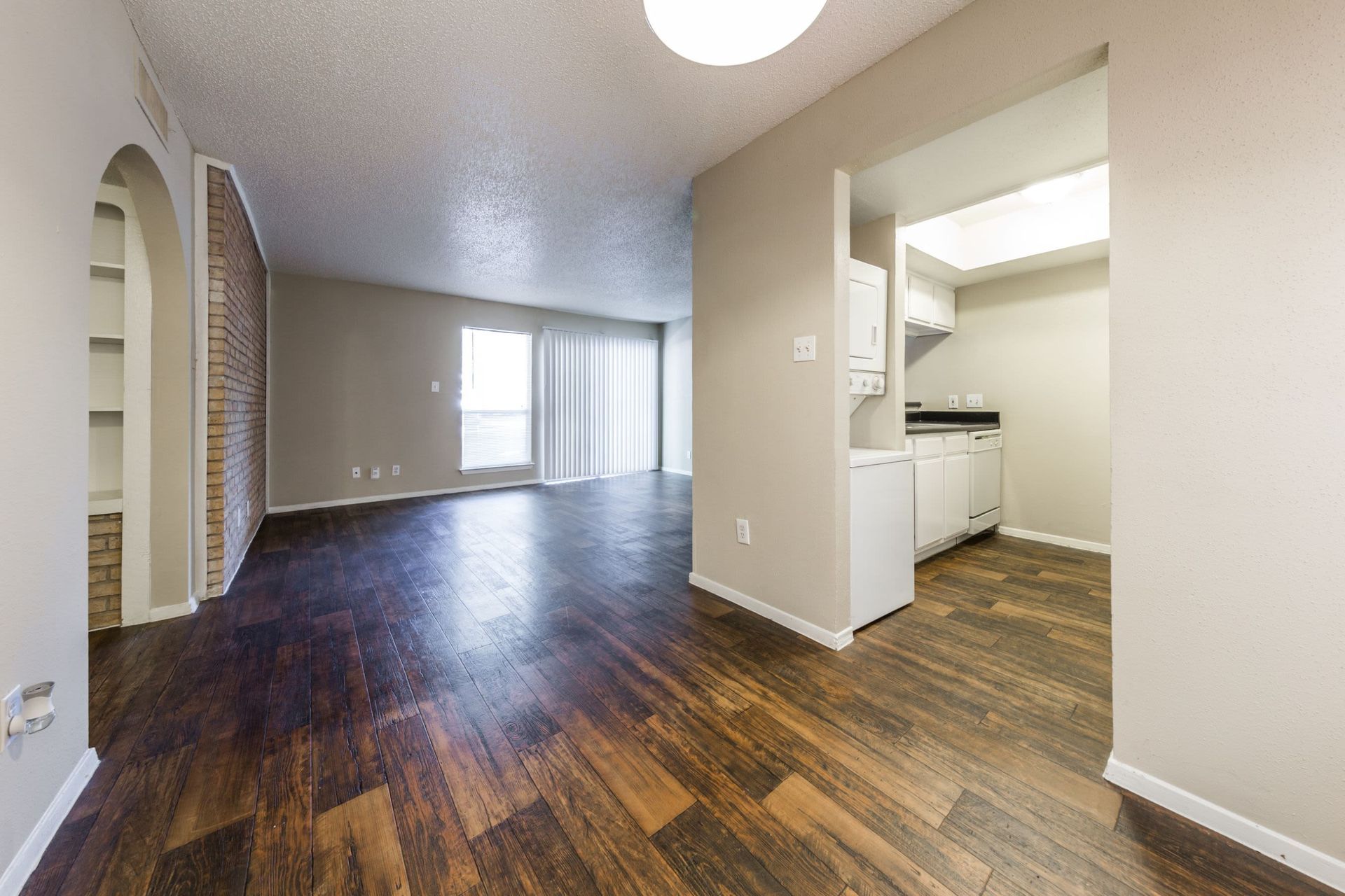 An empty apartment layout with hardwood floors and a kitchen at SoCo on the Lake in Austin, TX.
