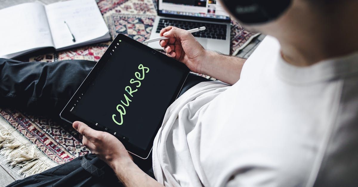 A man is sitting on the floor using a tablet with the word courses written on it.