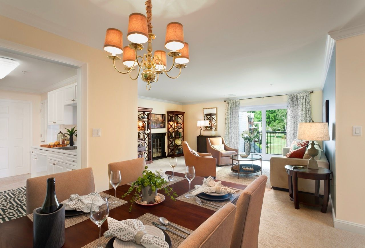 Open-concept living and dining area with a chandelier, comfortable seating, and sliding glass doors to a balcony.