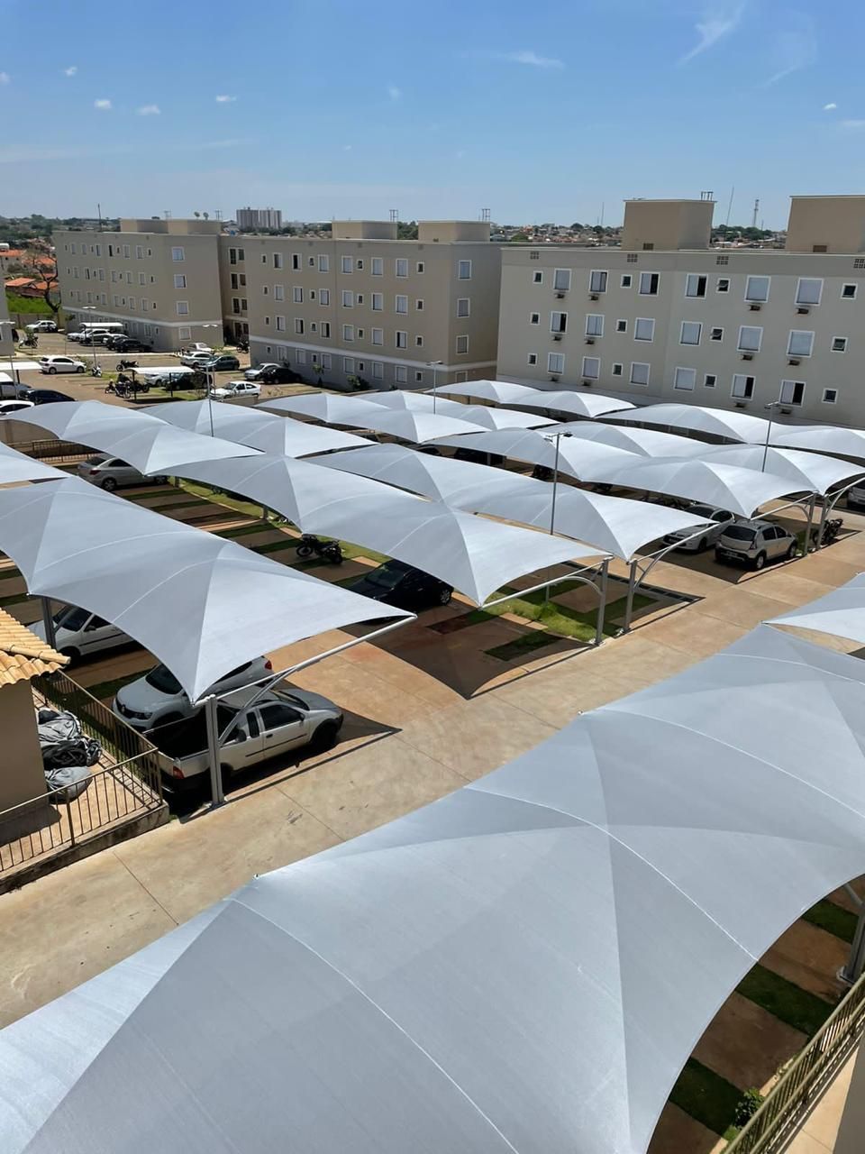 Uma fileira de guarda-chuvas brancos cobre um estacionamento.
