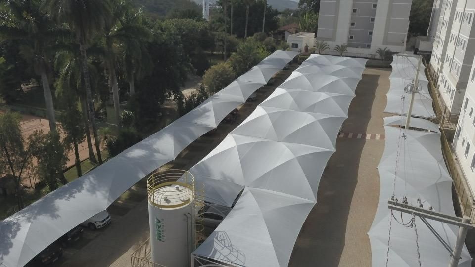 Uma vista aérea de um estacionamento coberto de guarda-chuvas brancos.