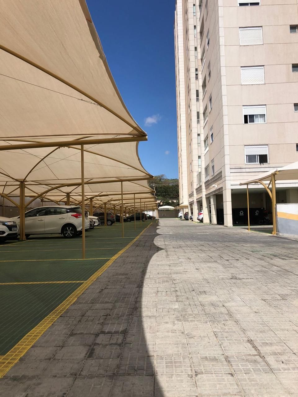 Muitos carros estão estacionados sob guarda-sóis em um estacionamento