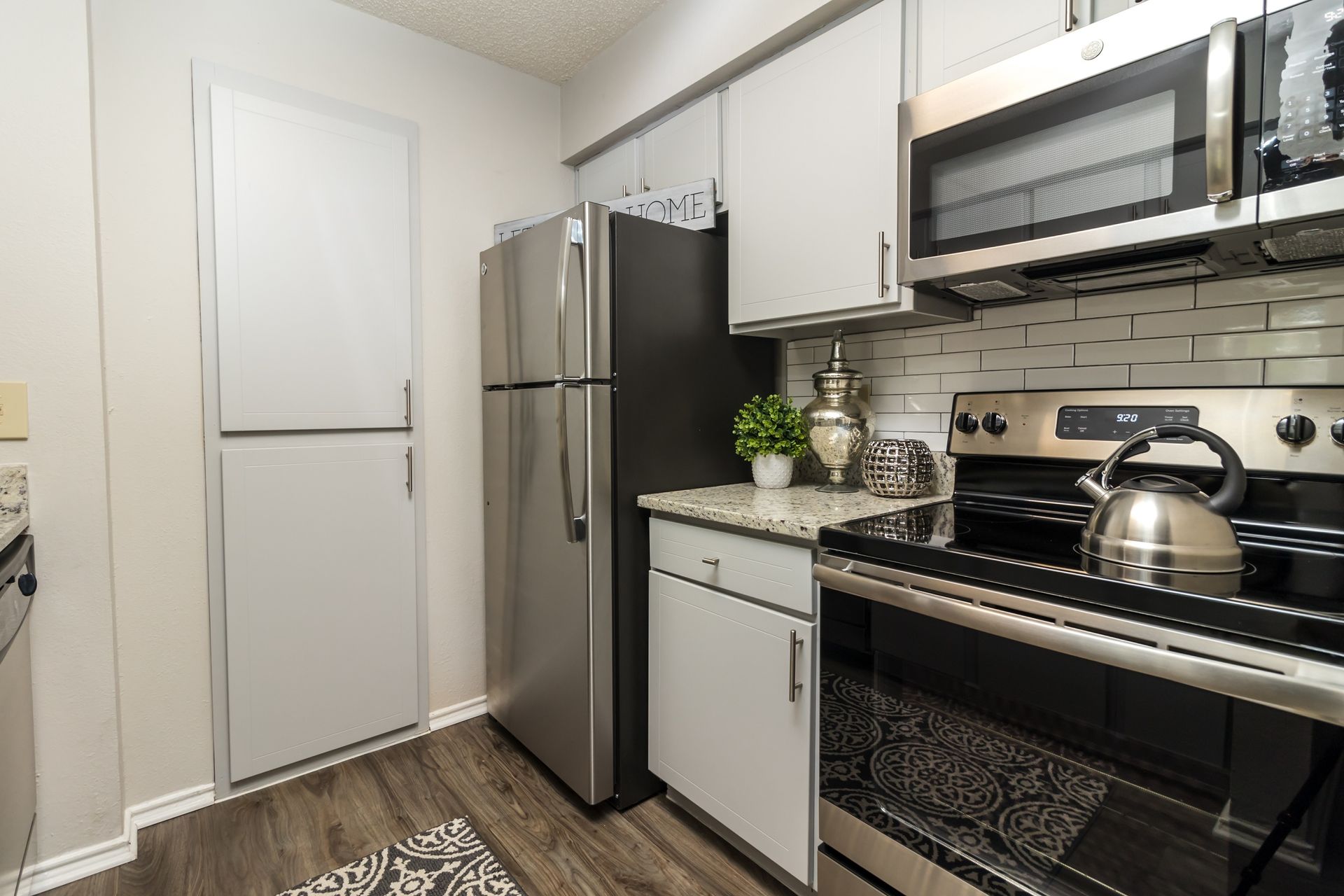 Kitchen with stainless steel appliances, white cabinets, and a black refrigerator.