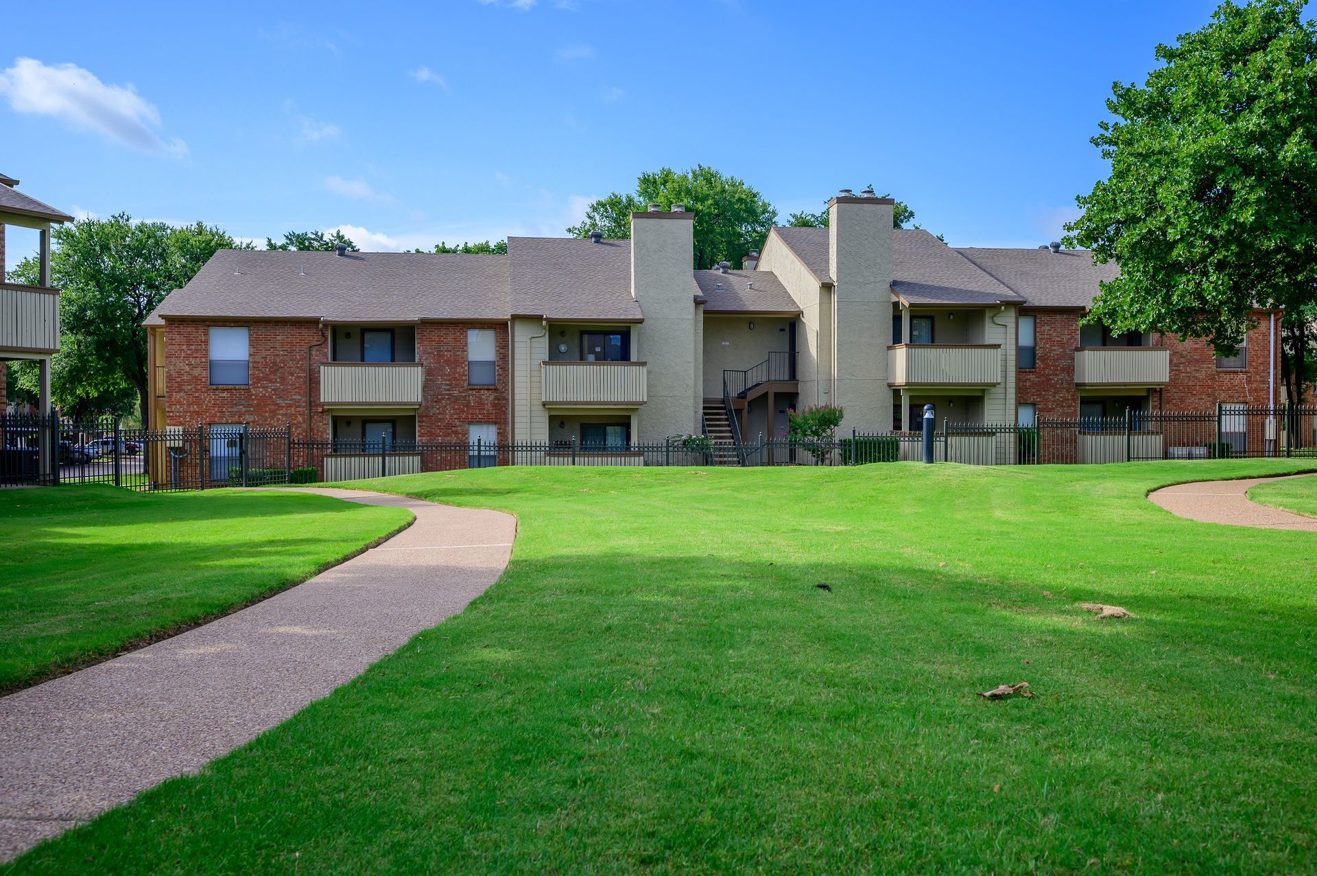 Apartment complex with brick exterior and green lawn on a sunny day.