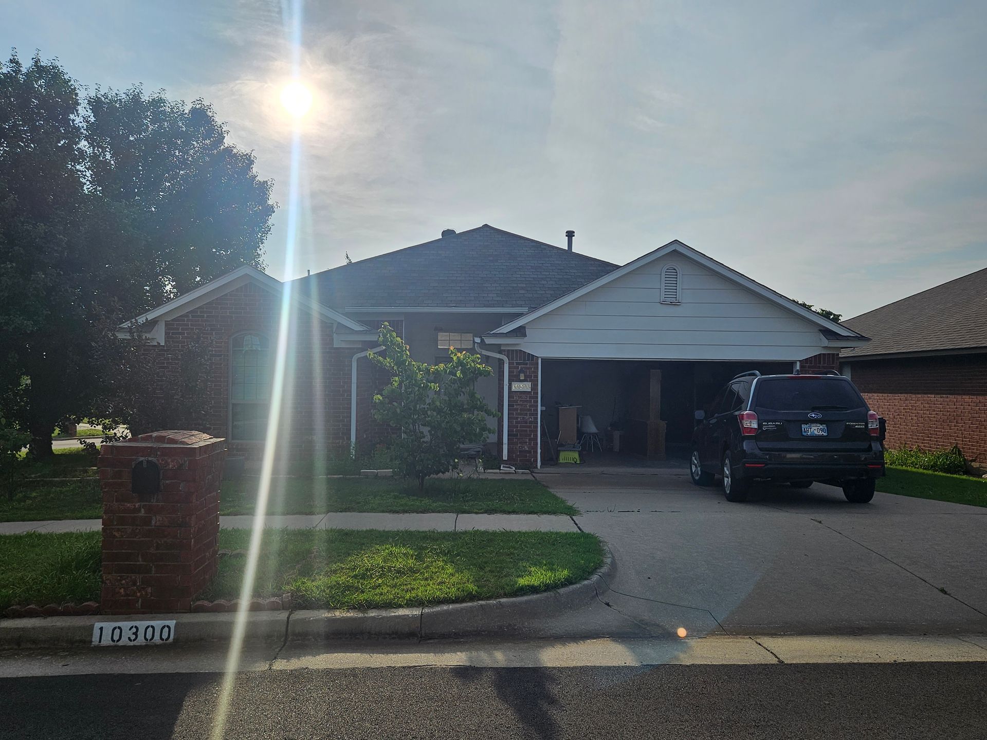 Suburban house with a driveway, a parked SUV, and a bright sun in the sky.