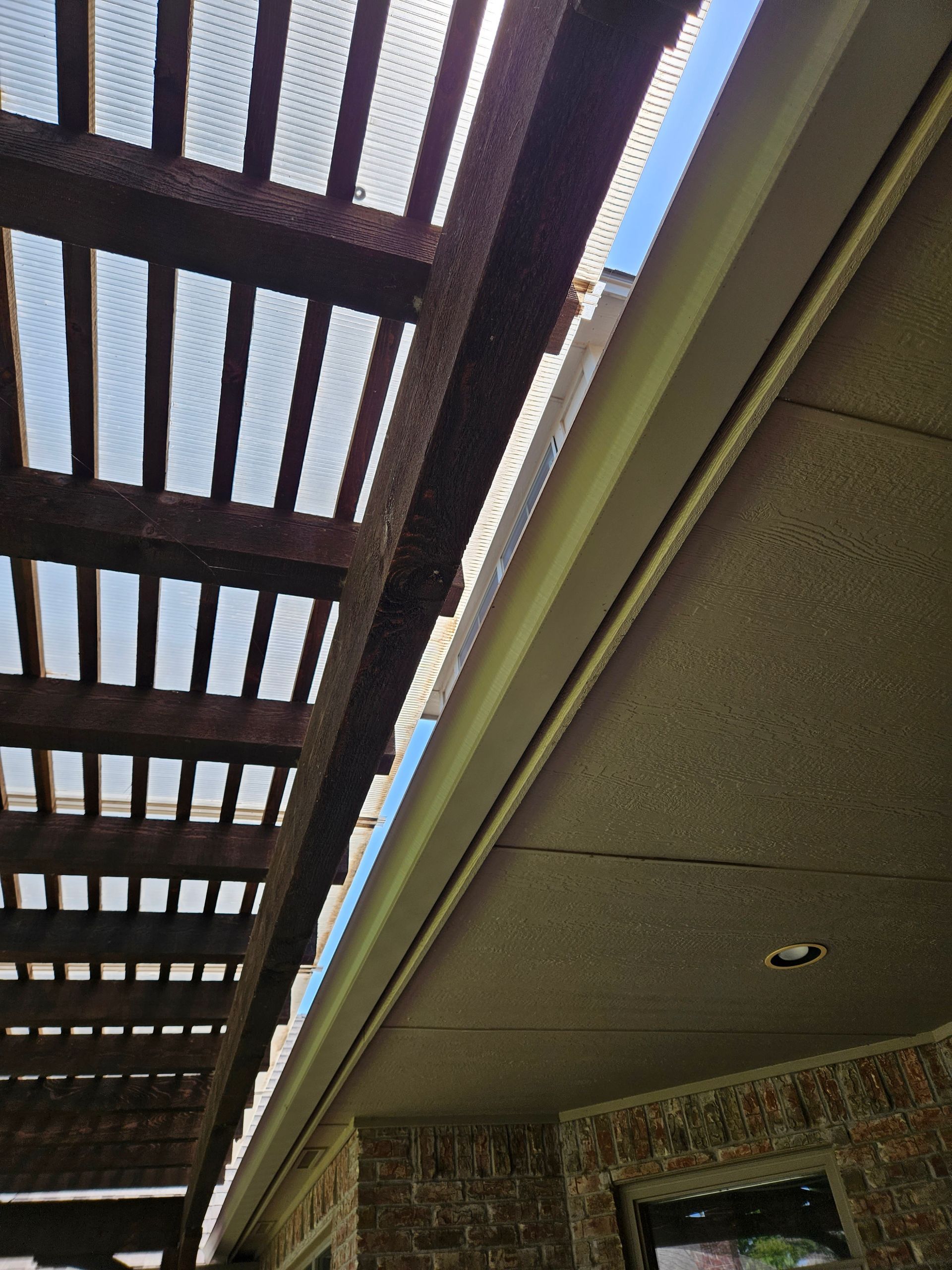 Wooden pergola with a gutter, viewed from below on a sunny day.