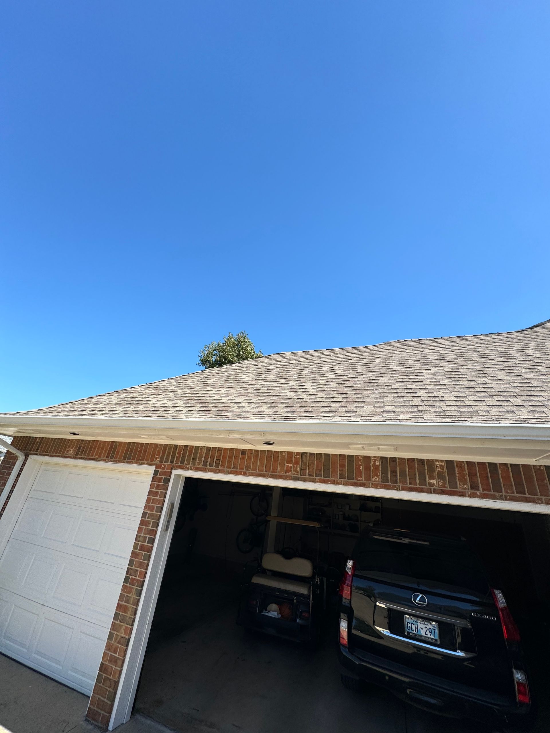 Garage with two bays; dark SUV parked inside. Clear blue sky overhead.
