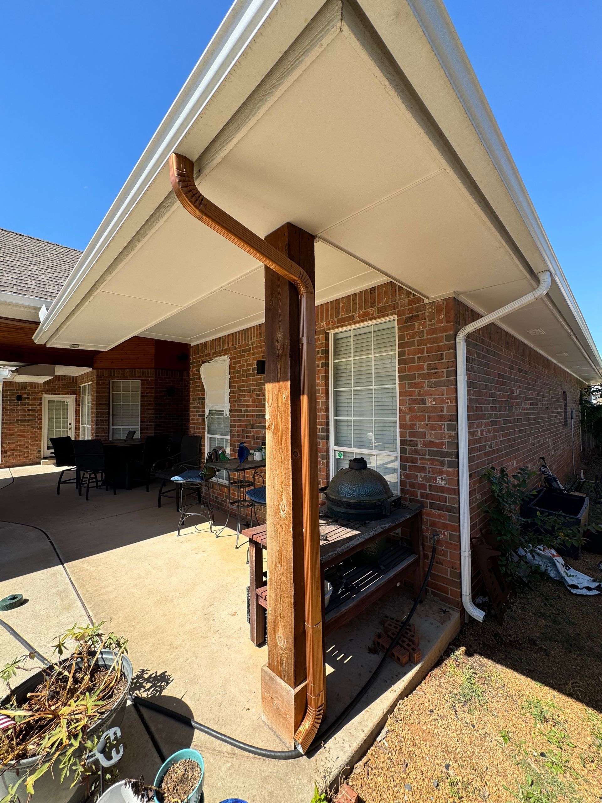 Patio with brick wall, white ceiling, brown post, and gutter.