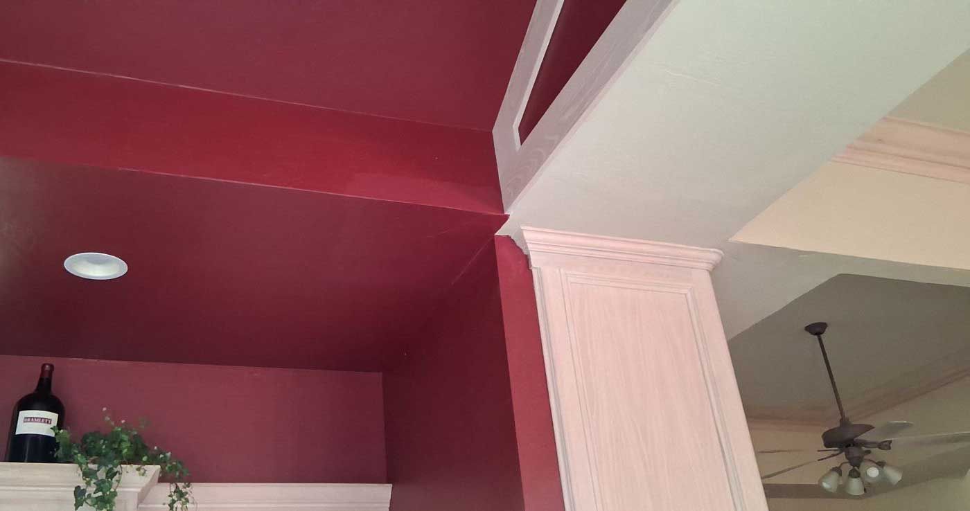Red walls and ceiling meet a white column with ornate trim; indoor setting.