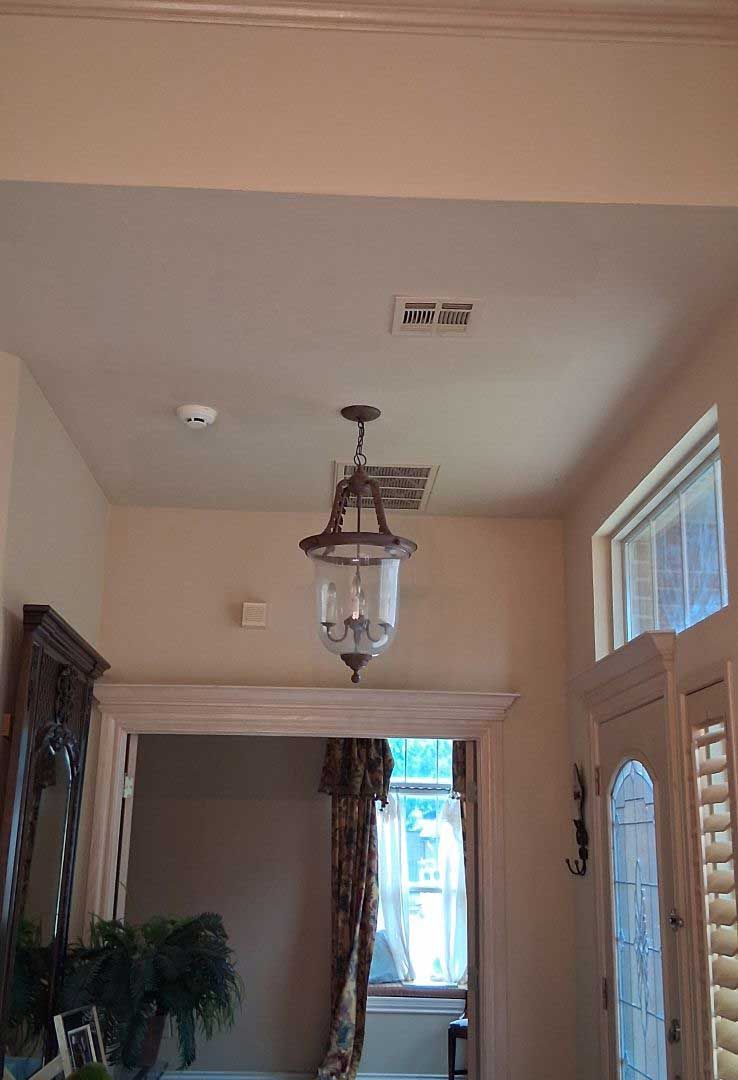 Entryway with a hanging lantern, open doorway, and a window with shutters. Beige walls and ceiling.