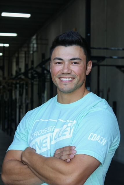 A man wearing a blue shirt that says crossfit on it