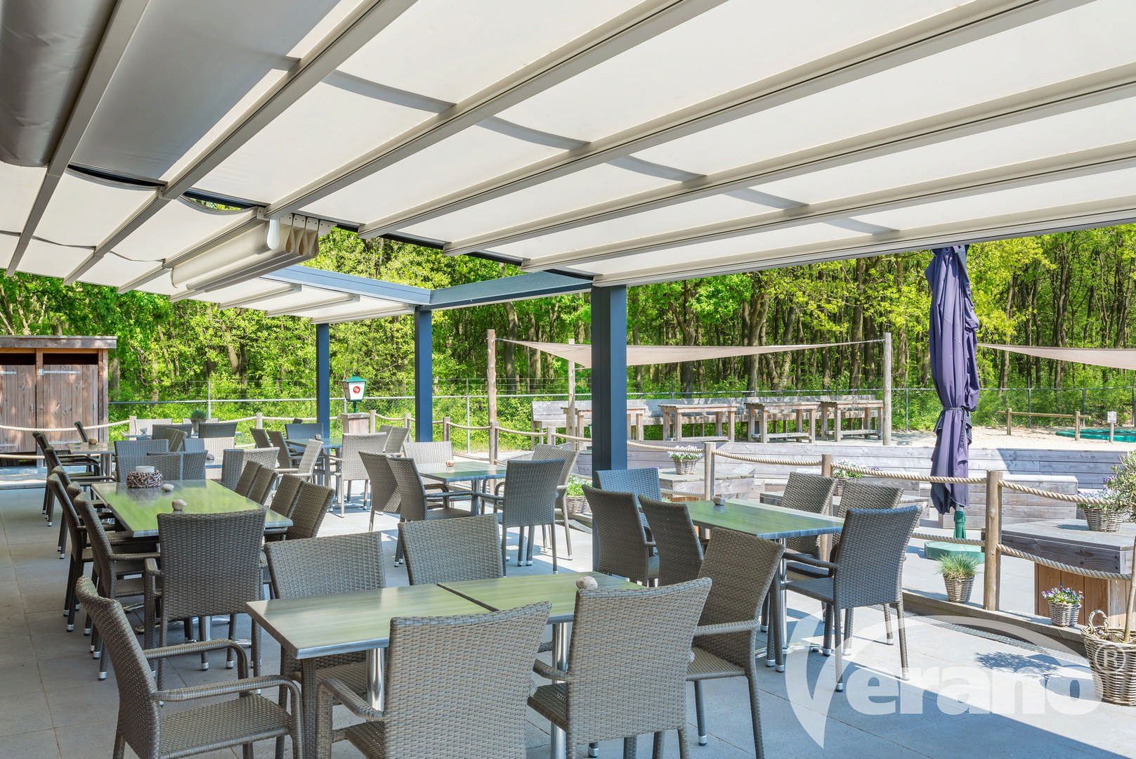 Een restaurant met tafels en stoelen onder een luifel