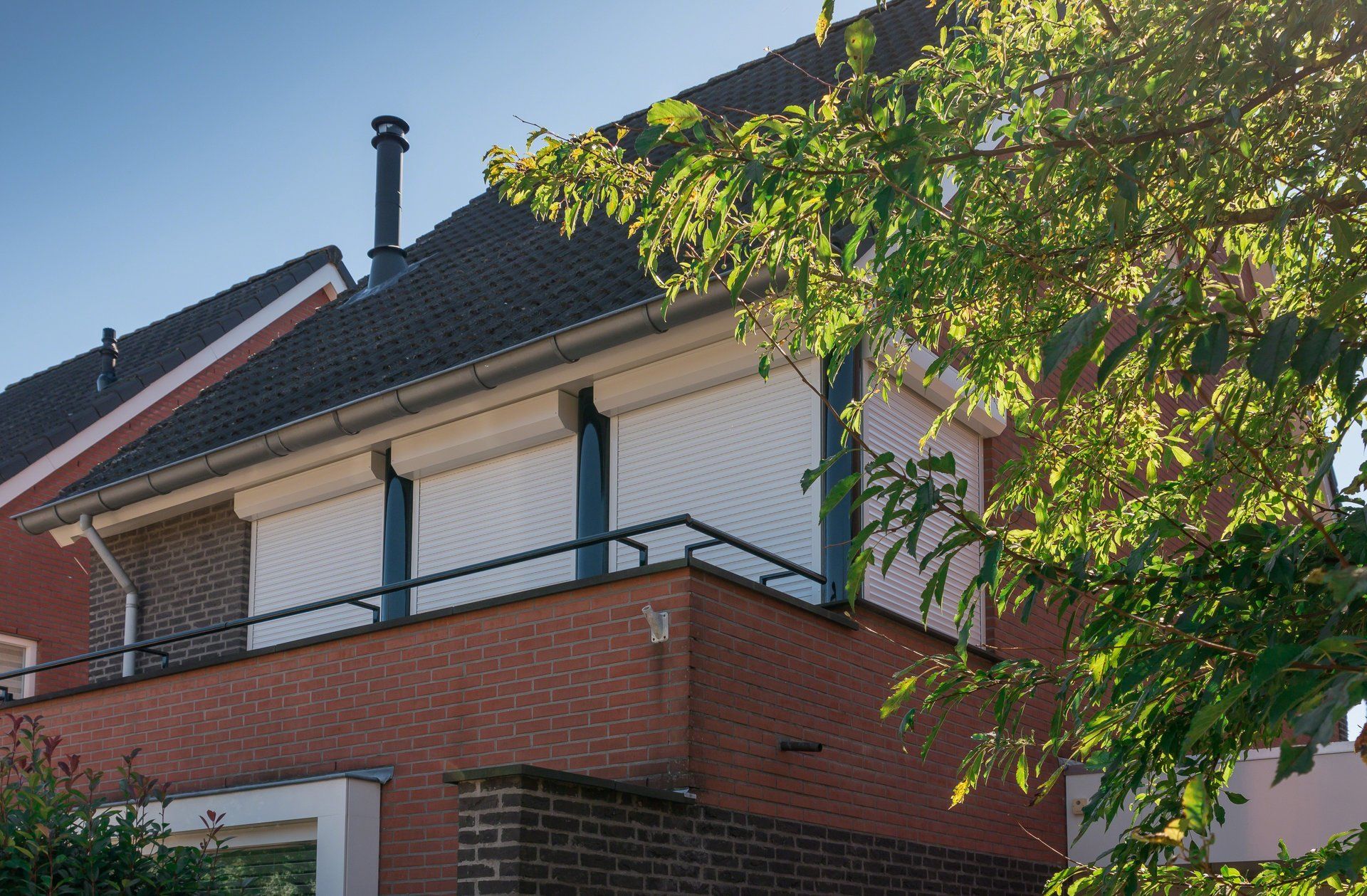 Een bakstenen huis met een balkon en luiken voor de ramen