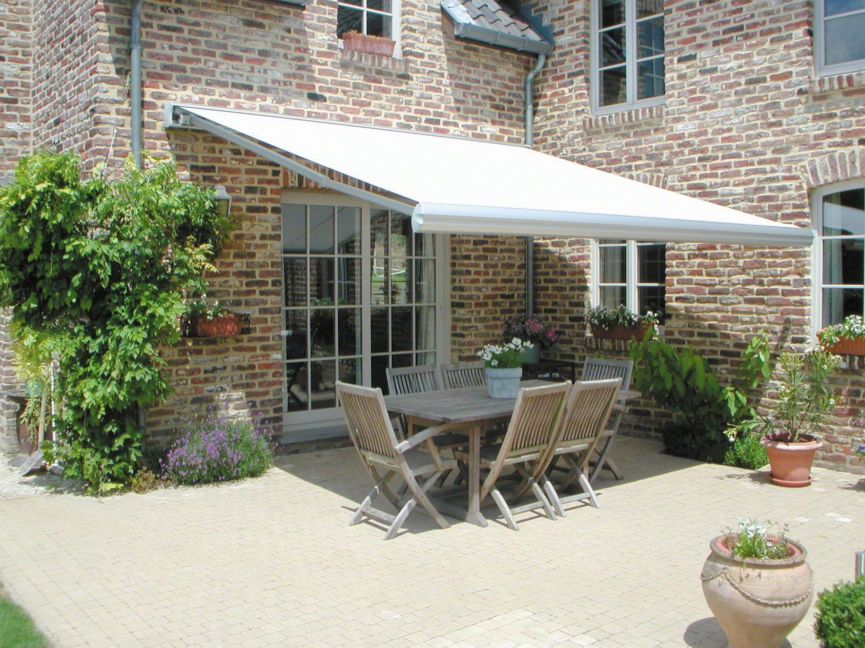 Een terras met een tafel en stoelen onder een luifel