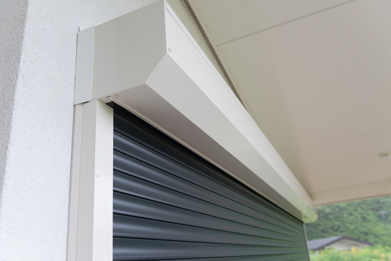 Een close-up van een zwart rolluik op een witte muur.