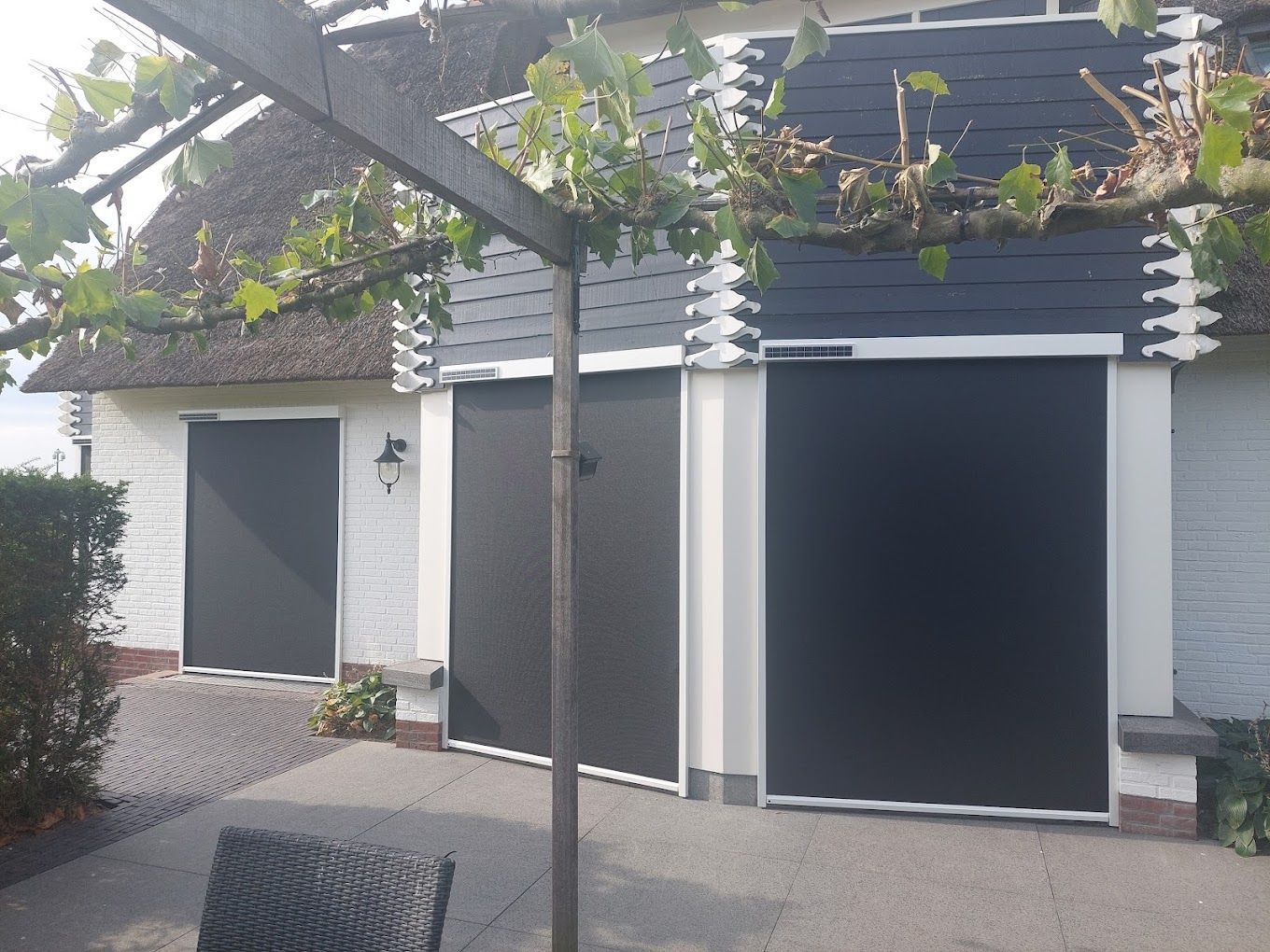 Een terras met een stoel en parasol voor een huis