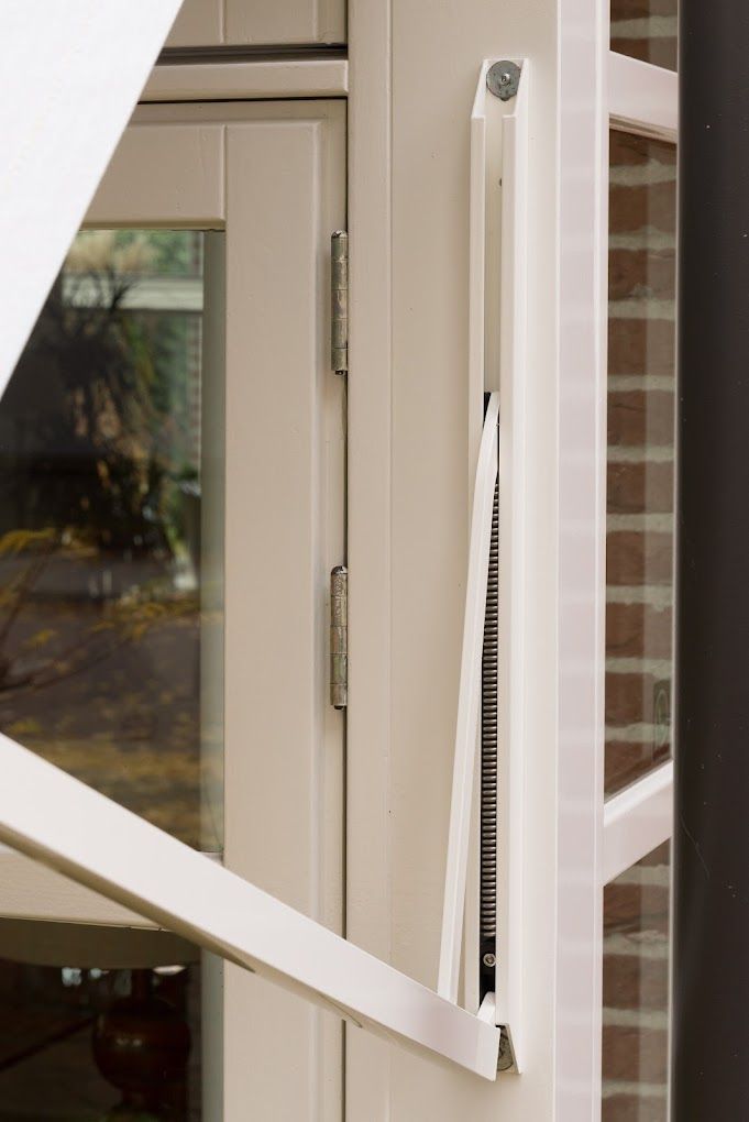 Een close-up van een wit raam met een bakstenen muur op de achtergrond