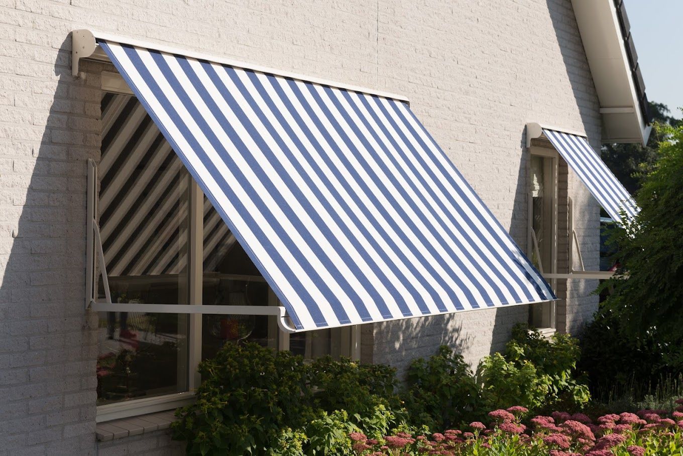 Een raam met een blauw-wit gestreepte luifel erboven