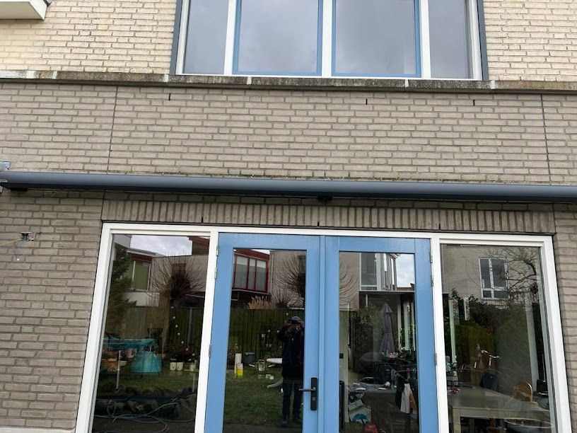 Een bakstenen gebouw met een blauwe deur en veel ramen.