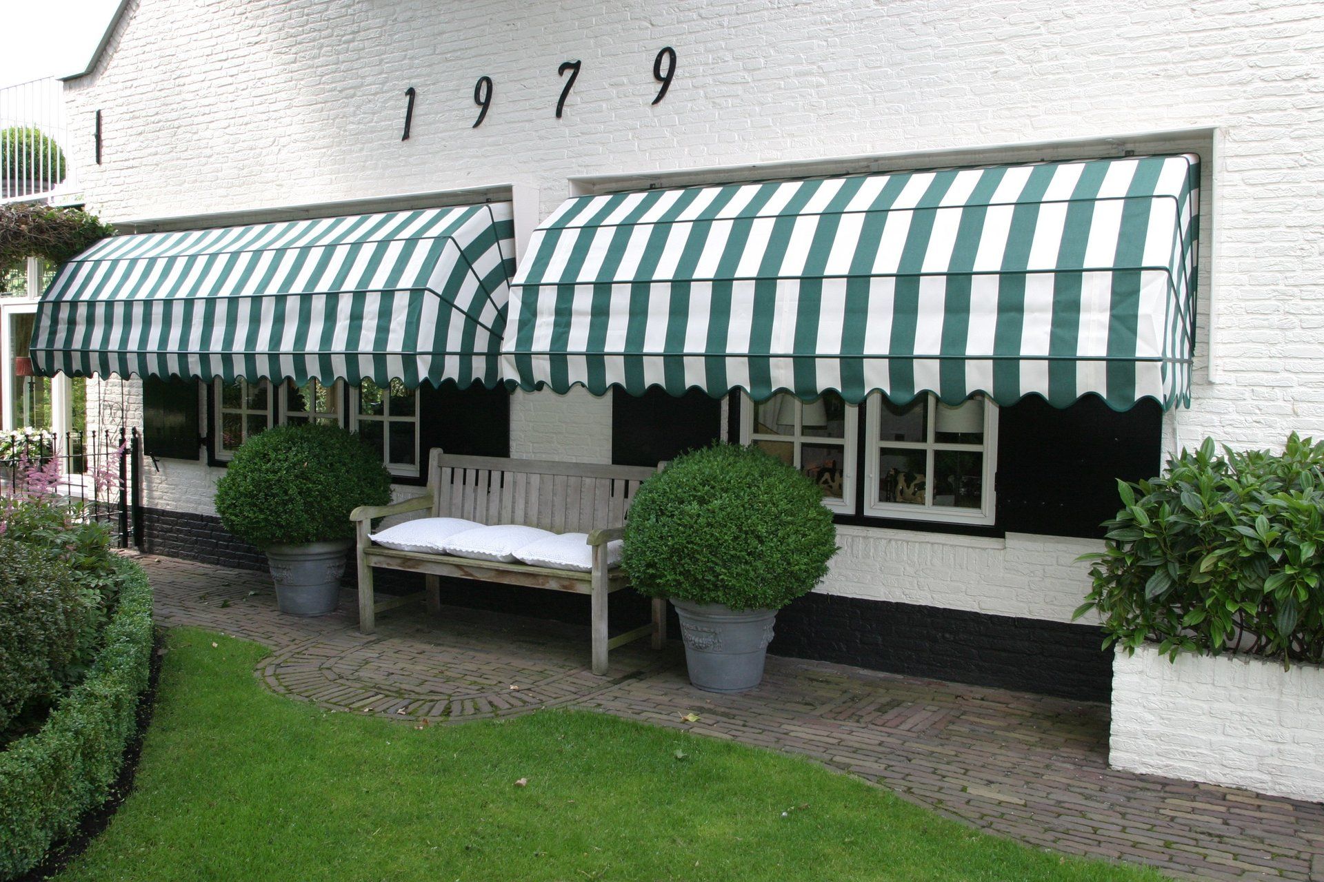 Een wit huis met een groen-wit gestreepte luifel