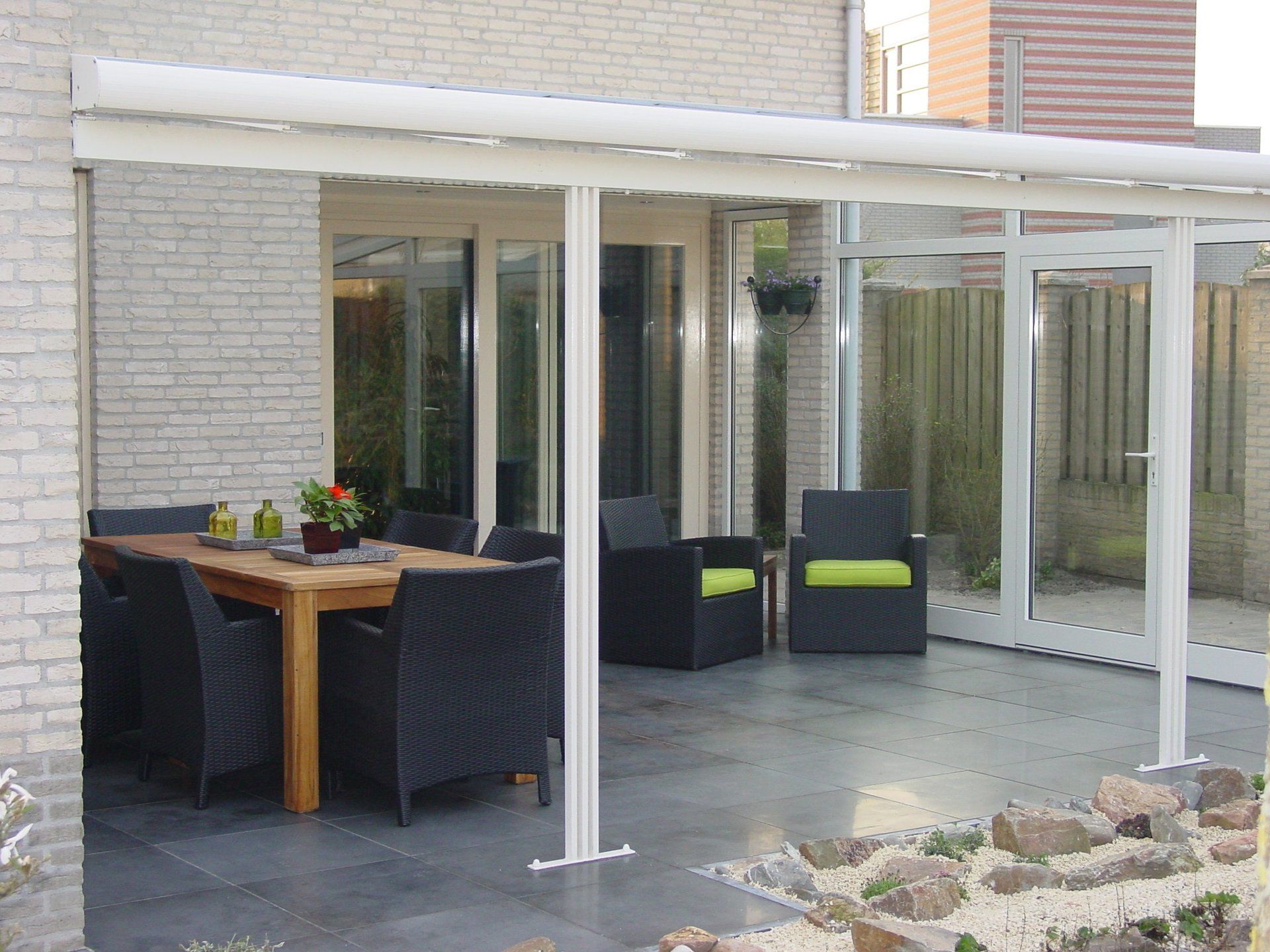 Een terras met een tafel en stoelen onder een luifel