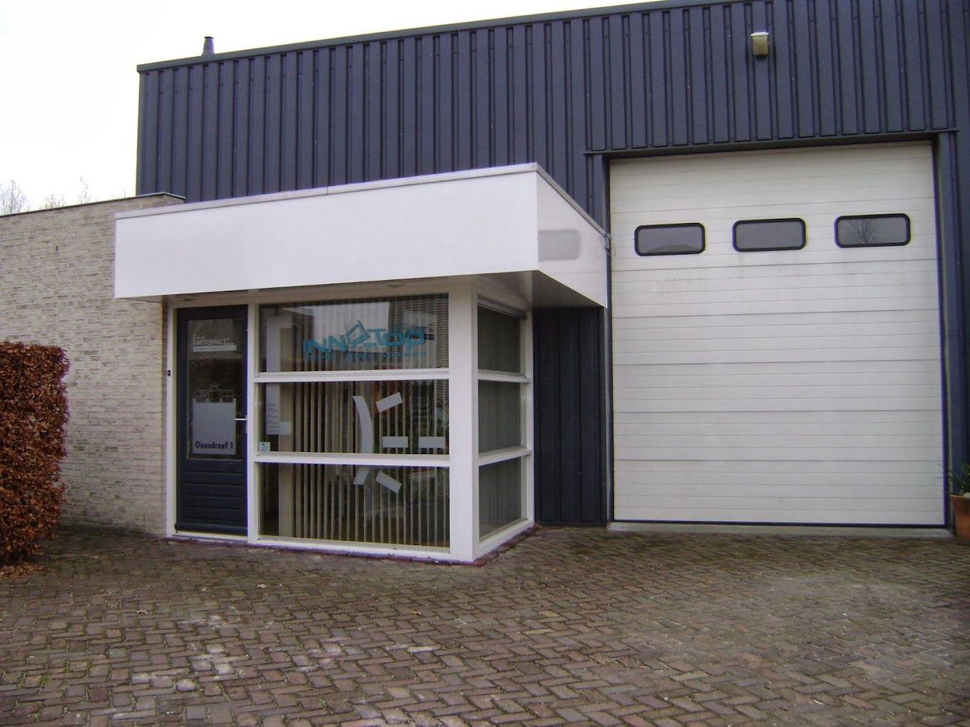 Een gebouw met een witte garagedeur en een witte luifel