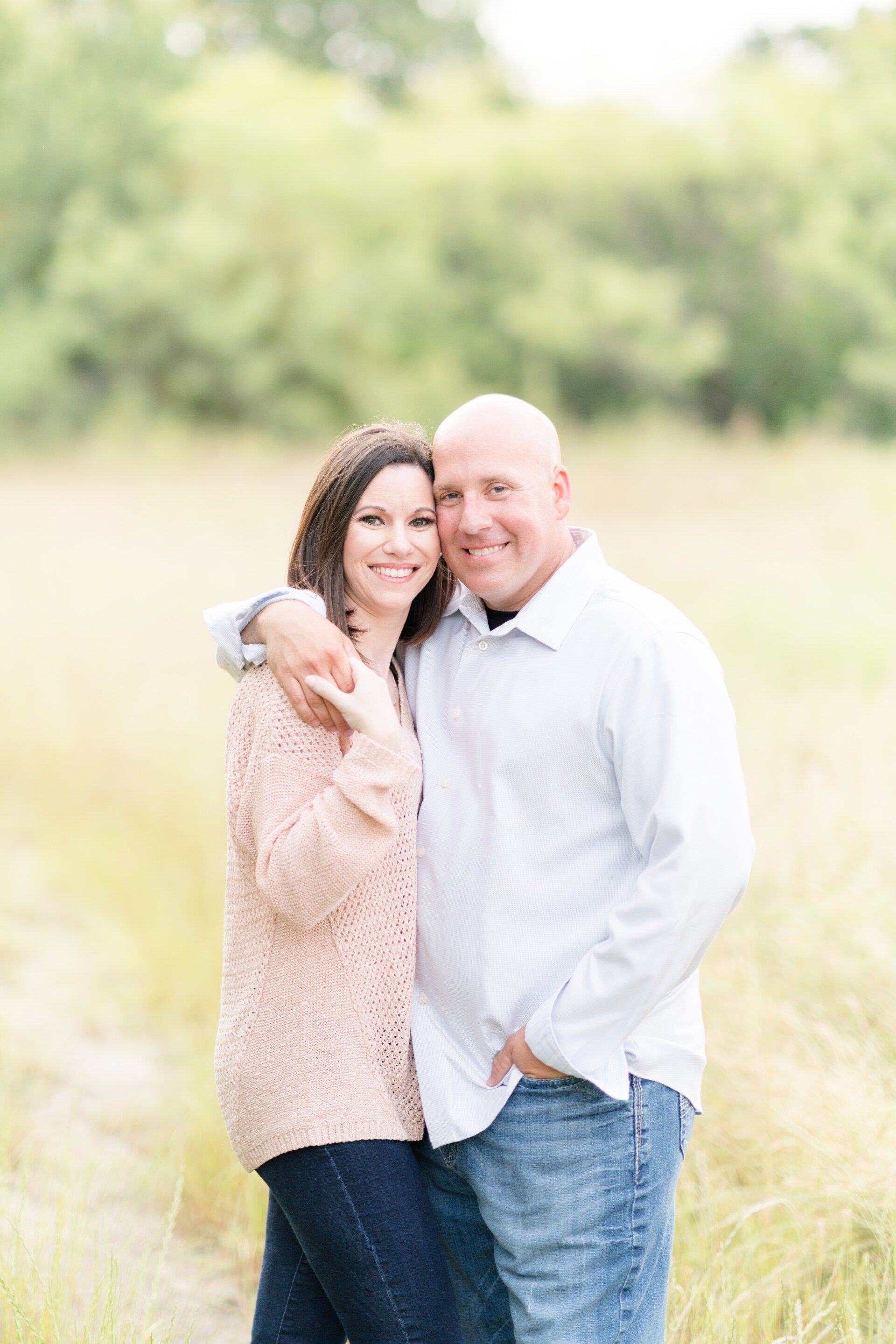 A man and a woman are posing for a picture in a field.